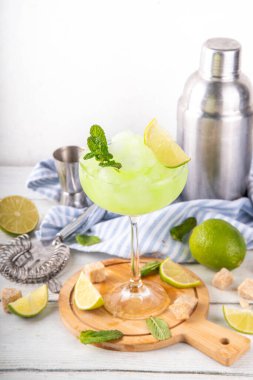 Mojito limonata, alkollü buzlu kokteyl, martini bardağında, yaz ferahlatıcı buzlu içecek, votka, limon suyu ve nane şurubu, bardaklarla dolu beyaz bir masada.