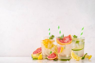 Yaz turunçgilleri arınma suyu, limon, limon, greyfurt, portakal, limonata, ahşap arka planda buzlu limonata içecekler. Buzlu mevsimlik içecek, meyve dilimleri ve naneli.