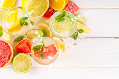 Yaz turunçgilleri arınma suyu, limon, limon, greyfurt, portakal, limonata, ahşap arka planda buzlu limonata içecekler. Buzlu mevsimlik içecek, meyve dilimleri ve naneli.