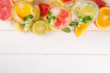 Yaz turunçgilleri arınma suyu, limon, limon, greyfurt, portakal, limonata, ahşap arka planda buzlu limonata içecekler. Buzlu mevsimlik içecek, meyve dilimleri ve naneli.