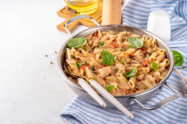 Son moda viral benimle tavuk makarnası evlen. Bir tencere yumuşak makarna ve kremalı ve peynirli sulu tavuk parçaları, sarımsaklı güneşte kurutulmuş domates sosu, nükteli fesleğen yaprağı, tabak ve demlikte.