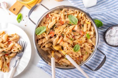 Son moda viral benimle tavuk makarnası evlen. Bir tencere yumuşak makarna ve kremalı ve peynirli sulu tavuk parçaları, sarımsaklı güneşte kurutulmuş domates sosu, nükteli fesleğen yaprağı, tabak ve demlikte.