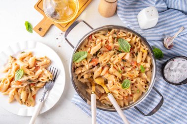 Son moda viral benimle tavuk makarnası evlen. Bir tencere yumuşak makarna ve kremalı ve peynirli sulu tavuk parçaları, sarımsaklı güneşte kurutulmuş domates sosu, nükteli fesleğen yaprağı, tabak ve demlikte.