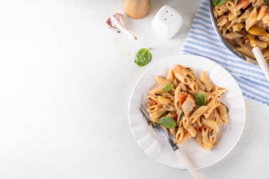 Son moda viral benimle tavuk makarnası evlen. Bir tencere yumuşak makarna ve kremalı ve peynirli sulu tavuk parçaları, sarımsaklı güneşte kurutulmuş domates sosu, nükteli fesleğen yaprağı, tabak ve demlikte.