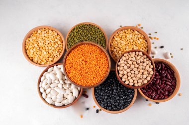 Çeşitli kuru fasulyeler, mercimek, mung, nohut, ahşap kaselerde bezelye çeşitleri. Legumes beyaz masa üst görünümünde. Vegan protein kaynakları yiyecek, kopyalama alanı