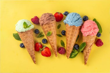  Parlak arka planda waffle külahlı renkli parlak dondurma. Taze böğürtlenli farklı dondurma külahları üst görünüm fotokopi alanı arka planı