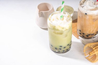 Klasik ve yeşil kibrit boba balonu çayı tapyoka incileri ve sütsüz krema bardağın üstünde, yaz aylarında tatlı tatlı içeceği beyaz masa arkasında fotokopi alanı