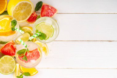 Yaz turunçgilleri arınma suyu, limon, limon, greyfurt, portakal, limonata, ahşap arka planda buzlu limonata içecekler. Buzlu mevsimlik içecek, meyve dilimleri ve naneli.