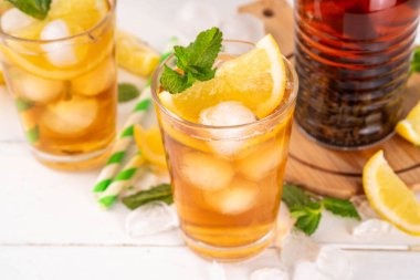 Buzlu çay kokteyli, soğuk yaz içeceği, siyah çay, limon, nane ve ezilmiş buz, beyaz ahşap arka planda alkolsüz hoş bir kokteyl. 