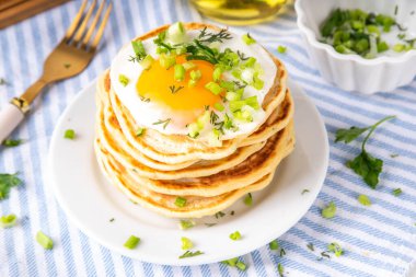 Lezzetli kahvaltı krepleri, taze soğan ve kızarmış yumurta. Lezzetli ya da tatlı olmayan krepleri beyaz mutfak masasında maydanozlu ve güneşli yumurtalarla fotokopi masasının üzerinde.