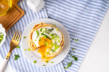 Lezzetli kahvaltı krepleri, taze soğan ve kızarmış yumurta. Lezzetli ya da tatlı olmayan krepleri beyaz mutfak masasında maydanozlu ve güneşli yumurtalarla fotokopi masasının üzerinde.