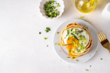 Lezzetli kahvaltı krepleri, taze soğan ve kızarmış yumurta. Lezzetli ya da tatlı olmayan krepleri beyaz mutfak masasında maydanozlu ve güneşli yumurtalarla fotokopi masasının üzerinde.