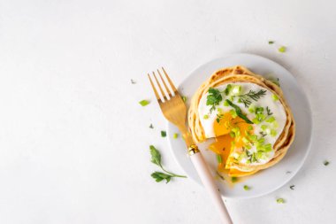 Lezzetli kahvaltı krepleri, taze soğan ve kızarmış yumurta. Lezzetli ya da tatlı olmayan krepleri beyaz mutfak masasında maydanozlu ve güneşli yumurtalarla fotokopi masasının üzerinde.