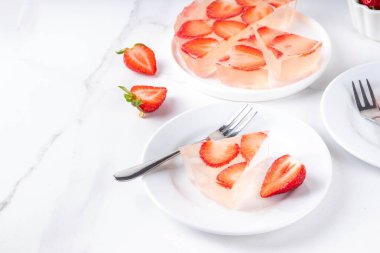 Japon yağmur damlası keki, ya da Mizu Shingen Mochi, berrak jöle tatlısı, kristal berrak su benzeri lezzetli, çilek dilimli tart, tabaklar üzerine porsiyonlu, beyaz mermer arka plan fotokopi alanı