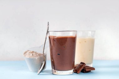 Hızlı ve basit protein pudingi. Sağlıklı yaz soğuk tatlısı. Üç bardak vanilyalı, çikolatalı ve çilekli puding, çikolata dilimleri, taze çilek, yabanmersini, protein tozu