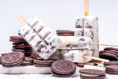 Krema ve kurabiye dondurması, vanilyalı dondurma lolipoplar çikolatalı ezilmiş kurabiyeler, mutfak masasında bir sürü kurabiye.