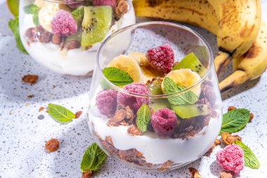Yaz sağlıklı diyet kahvaltısı, atıştırmalık konsepti. Yoğurt, taze böğürtlen ve meyveli üç katlı granola kahvaltılık tatlı. İki porsiyonlu bardak ve bir gecede yulaf ezmesi parfümlü tatlı.