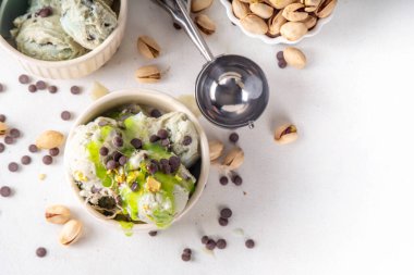 Dubai çikolatalı dondurma, tahini, kataifi ve çikolatalı dondurma, Dubai çikolatalı şurup soslu ve fıstıklı, beyaz mutfak masasında,