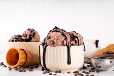 Beyaz masa arkasında dondurma külahlı duble çikolatalı dondurma kasesi. Ev yapımı çikolatalı dondurma ve çikolata sosu, tatlı ve lezzetli yaz tatlısı.