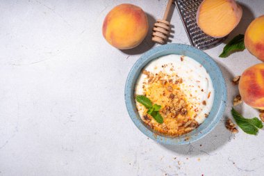 Dondurulmuş şeftali ve krema, kremalı ve yoğurtlu sağlıklı yaz atıştırması ve dondurulmuş şeftali meyveleri, fındık, bal ve nane, kopyalama alanı.