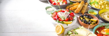 Farklı Akdeniz yemekleri: zeytin, mozarella domates salatası, Yunan salatası, makarna, tortellini ravioli, pizza, pita sandviçi, şiş kebap, shakshuka, humus, üst manzara