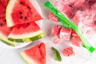 Donmuş karpuz dilimleri, donmuş poşetlerdeki taze çiğ karpuzlar mutfak masasındaki beyaz masa, sağlıklı basit konserve, kış konsepti için dondurulmuş meyve hasadı stokları.. 