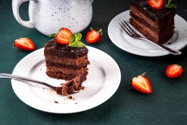 Koyu çikolatalı pasta dilimleri, çikolatalı krema ve çilekli, porsiyonlu tabaklarda, kopyalama alanı