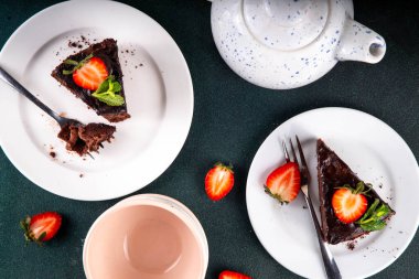 Koyu çikolatalı pasta dilimleri, çikolatalı krema ve çilekli, porsiyonlu tabaklarda, kopyalama alanı