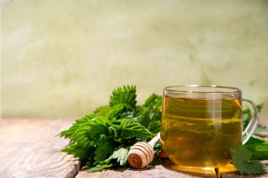 Nettle Tea sıcak bitkisi şeffaf cam bardakta içecek. Organik doğal bitkisel çay kafeinsiz, organik çiğ ısırgan otu yapraklarıyla yapılır. Alternatif bitkisel ilaç. Isırgan otu, urtica.