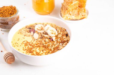 Arı polenli, altın kremalı ya da meyveli, granola ve muzlu sağlıklı meyve suyu kasesi. Temiz yemek, diyet vejetaryen yemeği ve arı poleni organik tozu. 