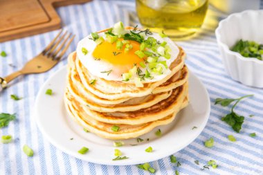 Lezzetli kahvaltı krepleri, taze soğan ve kızarmış yumurta. Lezzetli ya da tatlı olmayan krepleri beyaz mutfak masasında maydanozlu ve güneşli yumurtalarla fotokopi masasının üzerinde.