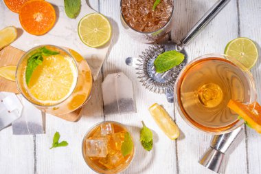 Modaya uygun çay seti yeşil, oolong, siyah, çay ve diğer çay karışımlarından esinlenilmiştir. Soda, şerbetli soğuk yaz içecekleri, limon, kireç ve nane, güneşli beyaz ahşap arka plan.