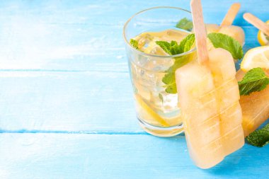 Buzlu çay veya limonata, tatlı limon ve naneli kokteyl lolipopları soğuk içecek, limon dilimleri ve nane yaprakları fotokopi alanı