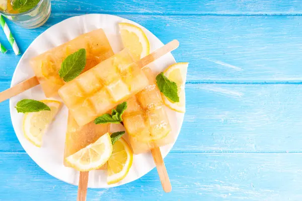 Buzlu çay veya limonata, tatlı limon ve naneli kokteyl lolipopları soğuk içecek, limon dilimleri ve nane yaprakları fotokopi alanı