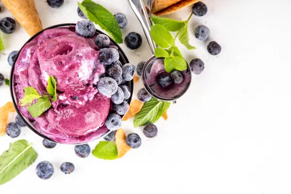 Yaban mersini zengini kremalı şerbet, taze böğürtlenli lezzetli yaban mersini dondurması, nane yaprağı ve beyaz masa fotokopi alanı üzerinde dondurmalı waffle konileri.