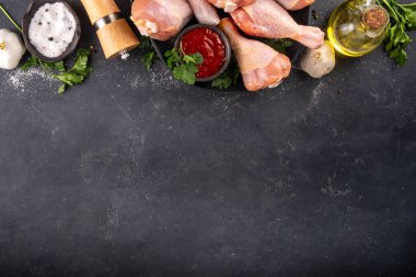 Tavuk eti hazırlama arka planı, ızgaraya hazır çiğ tavuk bacağı, baharatlar, tuz, biber, zeytinyağı, sarımsak ve salamura veya sos. Izgara ve bbq sezon pişirme arka planı, kopyalama alanı