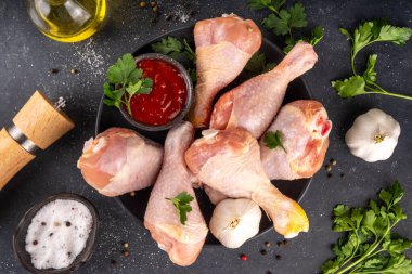 Tavuk eti hazırlama arka planı, ızgaraya hazır çiğ tavuk bacağı, baharatlar, tuz, biber, zeytinyağı, sarımsak ve salamura veya sos. Izgara ve bbq sezon pişirme arka planı, kopyalama alanı