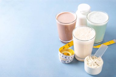 Protein tozu kepçesi ve mezurayla protein kokteyllerinin çeşitli çeşitleri. Protein, kilo vermek için sallanıyor, her gün protein hedefleri, spor ve spor, sağlıklı yaşam tarzı.
