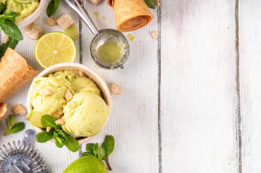Yaz ferahlatıcı soğuk tatlı, lezzetli aromatik mojito veya limonlu turtalı dondurma, seramik kasede mojito kokteyli aromalı ev yapımı şerbet, taze limon, nane, ahşap zemin üzerinde waffle konileri.