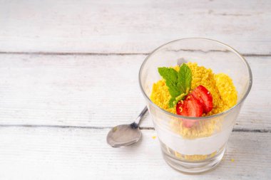 Klasik cam kaplı cheesecake, taze çilekli ve altın kurabiyeli. Katmanlı cheesecake tatlısıyla beyaz ahşap masa üzerinde taze çilekler fotokopi alanı