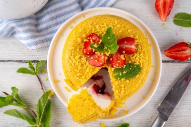 Tepetaklak Pasta yok, klasik Cheesecake New York 'un viral modası altın kurabiye parçacıkları, beyaz krem peynir ve böğürtlen reçeli katmanları, taze çilek ve ahşap masa üzerinde nane