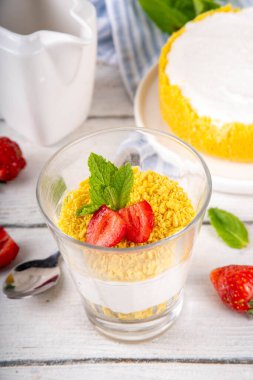Klasik cam kaplı cheesecake, taze çilekli ve altın kurabiyeli. Katmanlı cheesecake tatlısıyla beyaz ahşap masa üzerinde taze çilekler fotokopi alanı