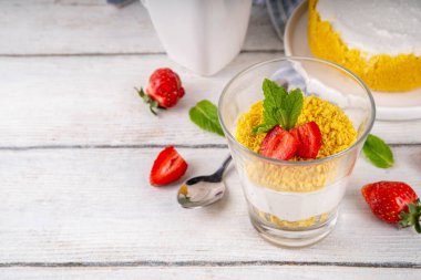 Klasik cam kaplı cheesecake, taze çilekli ve altın kurabiyeli. Katmanlı cheesecake tatlısıyla beyaz ahşap masa üzerinde taze çilekler fotokopi alanı