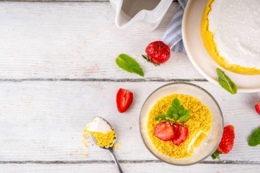 Klasik cam kaplı cheesecake, taze çilekli ve altın kurabiyeli. Katmanlı cheesecake tatlısıyla beyaz ahşap masa üzerinde taze çilekler fotokopi alanı