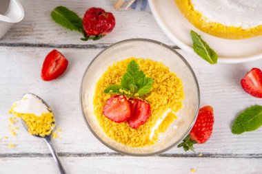 Klasik cam kaplı cheesecake, taze çilekli ve altın kurabiyeli. Katmanlı cheesecake tatlısıyla beyaz ahşap masa üzerinde taze çilekler fotokopi alanı