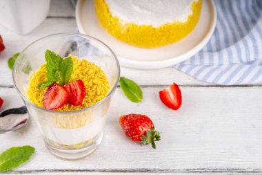 Klasik cam kaplı cheesecake, taze çilekli ve altın kurabiyeli. Katmanlı cheesecake tatlısıyla beyaz ahşap masa üzerinde taze çilekler fotokopi alanı