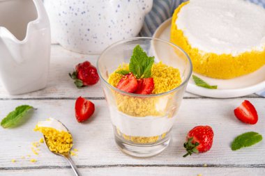 Klasik cam kaplı cheesecake, taze çilekli ve altın kurabiyeli. Katmanlı cheesecake tatlısıyla beyaz ahşap masa üzerinde taze çilekler fotokopi alanı