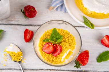 Klasik cam kaplı cheesecake, taze çilekli ve altın kurabiyeli. Katmanlı cheesecake tatlısıyla beyaz ahşap masa üzerinde taze çilekler fotokopi alanı