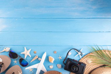 Yaz tatili ve hasır şapkalı, çantalı, terlikli, palmiye yapraklı, güneş gözlüklü, kameralı, deniz kabuklu ve okyanus yıldızlı tatil geçmişi. Plaj ve tropikal yaz tatili arka planı, üst görünüm kopyalama alanı