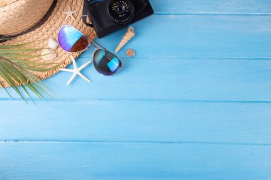 Yaz tatili ve hasır şapkalı, çantalı, terlikli, palmiye yapraklı, güneş gözlüklü, kameralı, deniz kabuklu ve okyanus yıldızlı tatil geçmişi. Plaj ve tropikal yaz tatili arka planı, üst görünüm kopyalama alanı